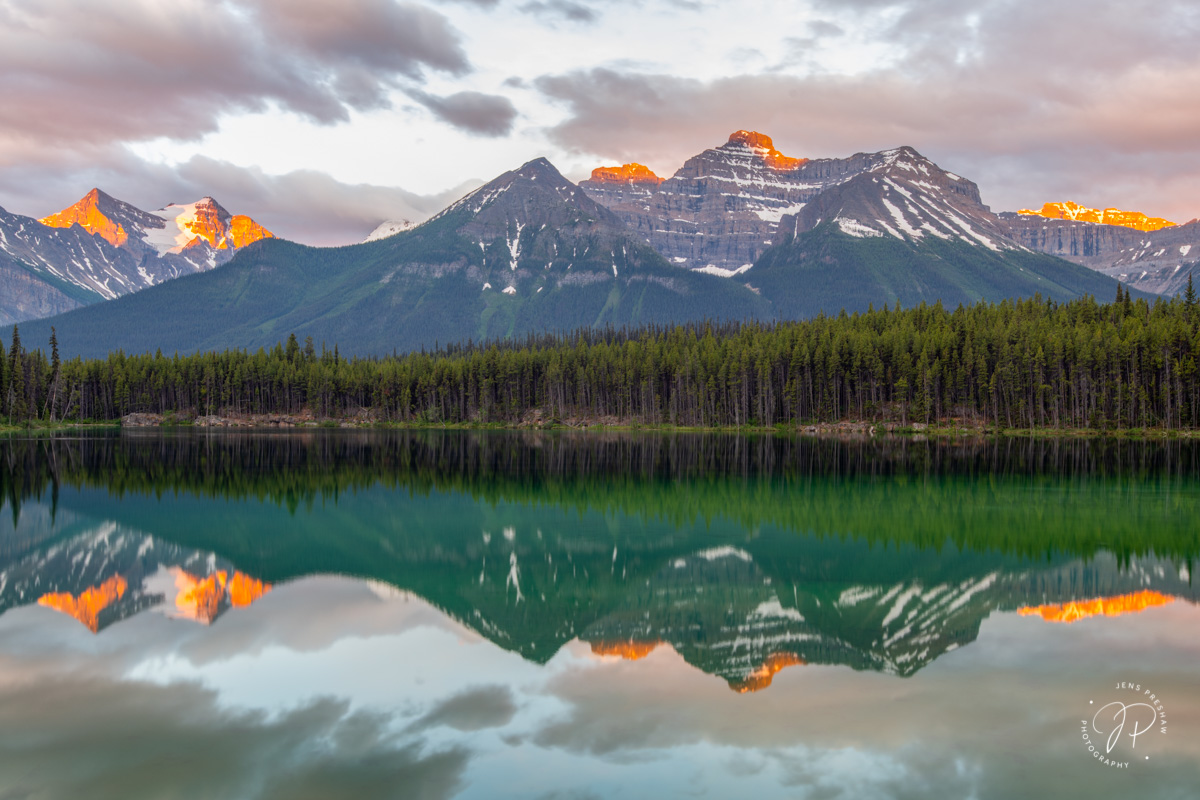 Herbert Lake reflecting the mountain range above. The tips of the mountains have this beautiful Alpenglow which only lasts a...